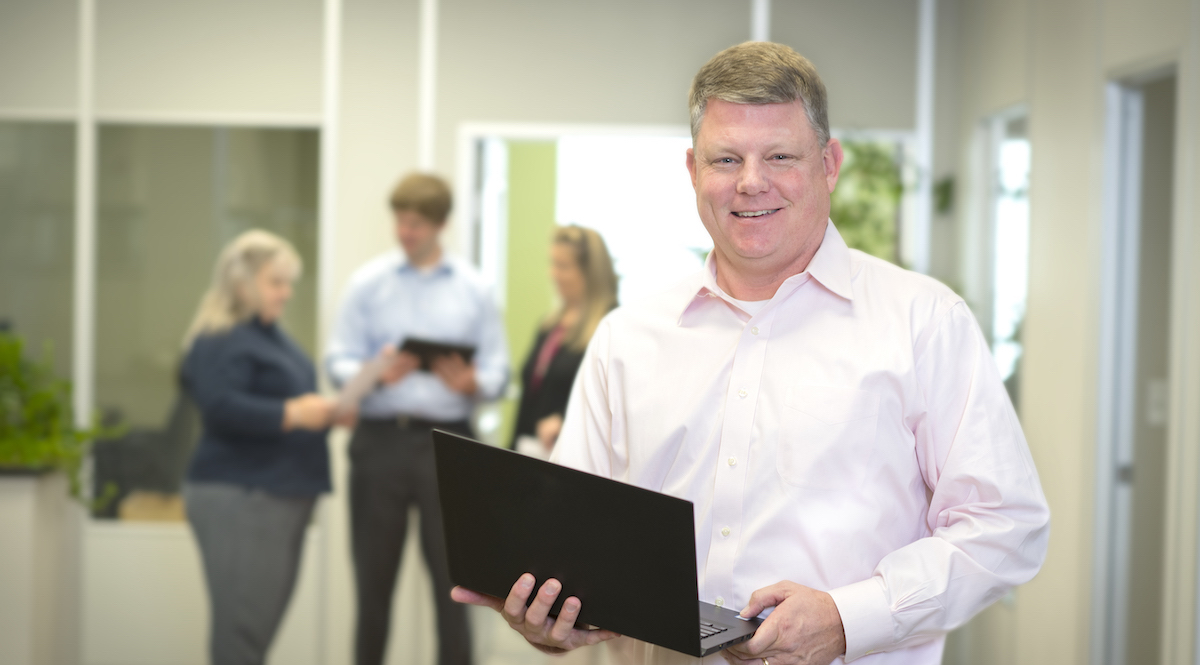 Magnolia Financial employee holding laptop in office